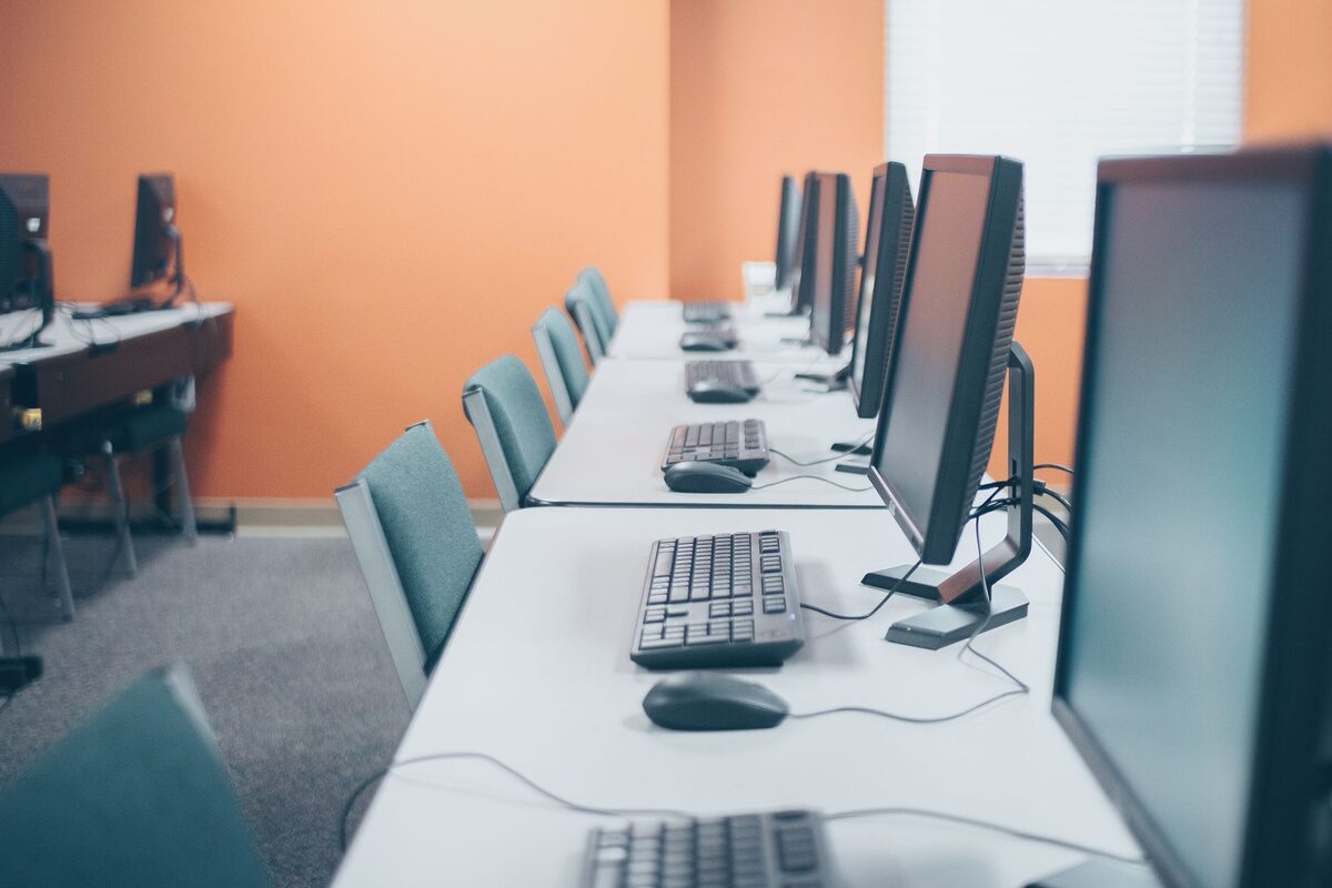 Rząd monitorów komputerowych w sali z pomarańczową ścianą