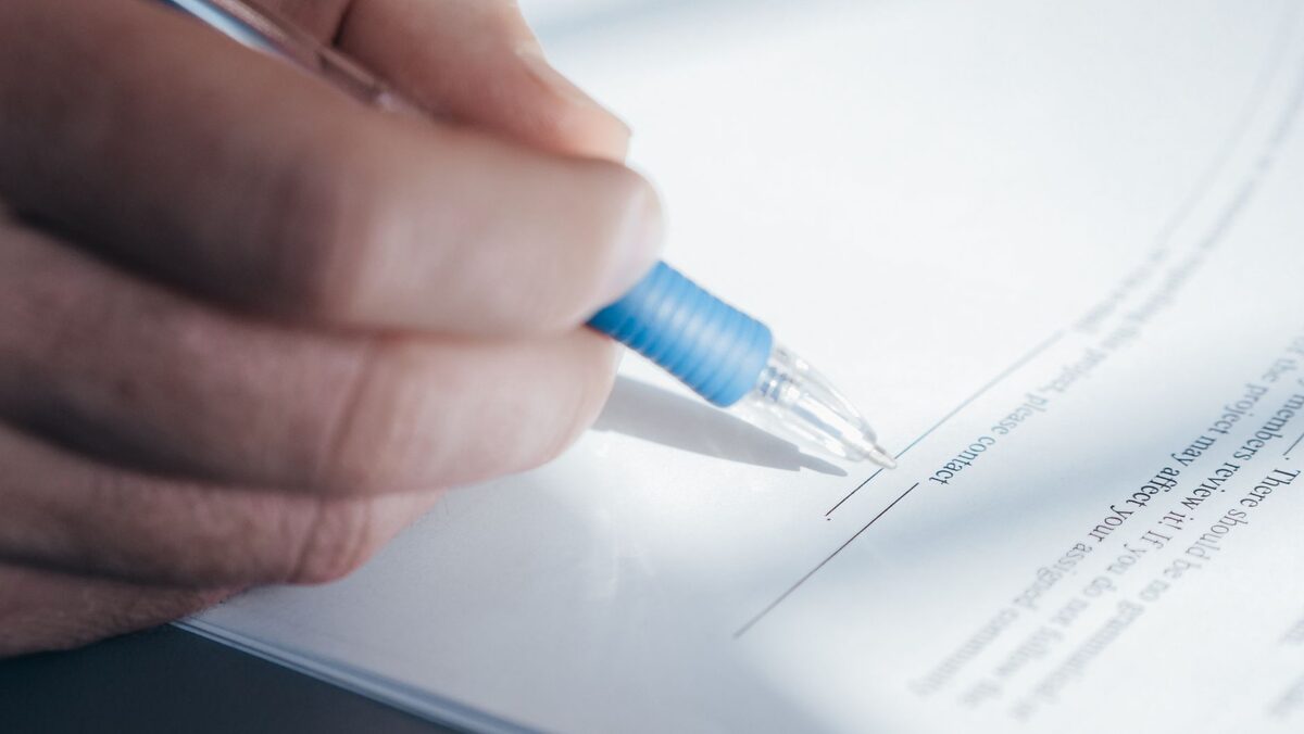 Dłoń podpisująca dokument długopisem — zatwierdzenie wyceny naprawy