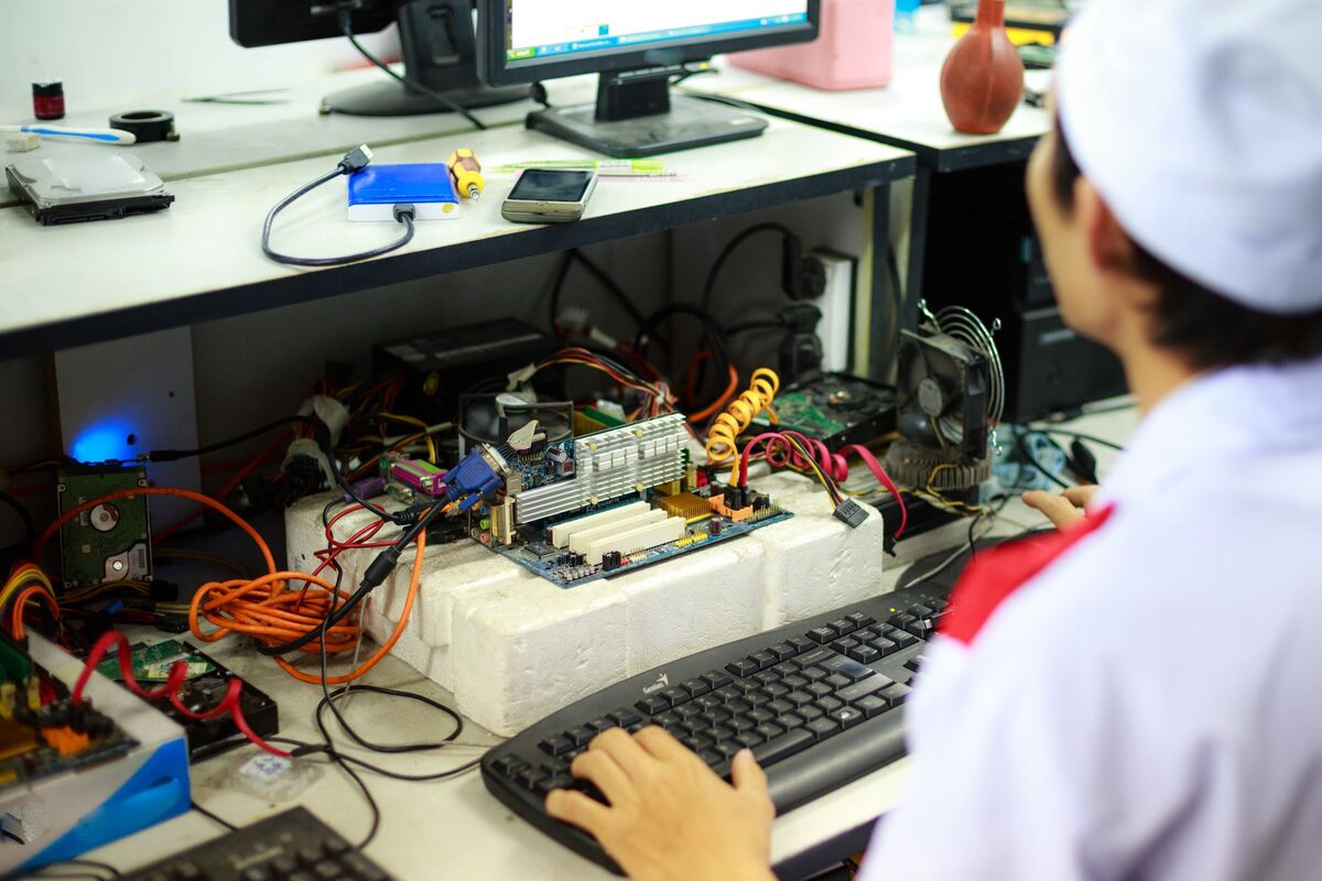 Osoba przy stanowisku serwisowym z podzespołami elektronicznymi