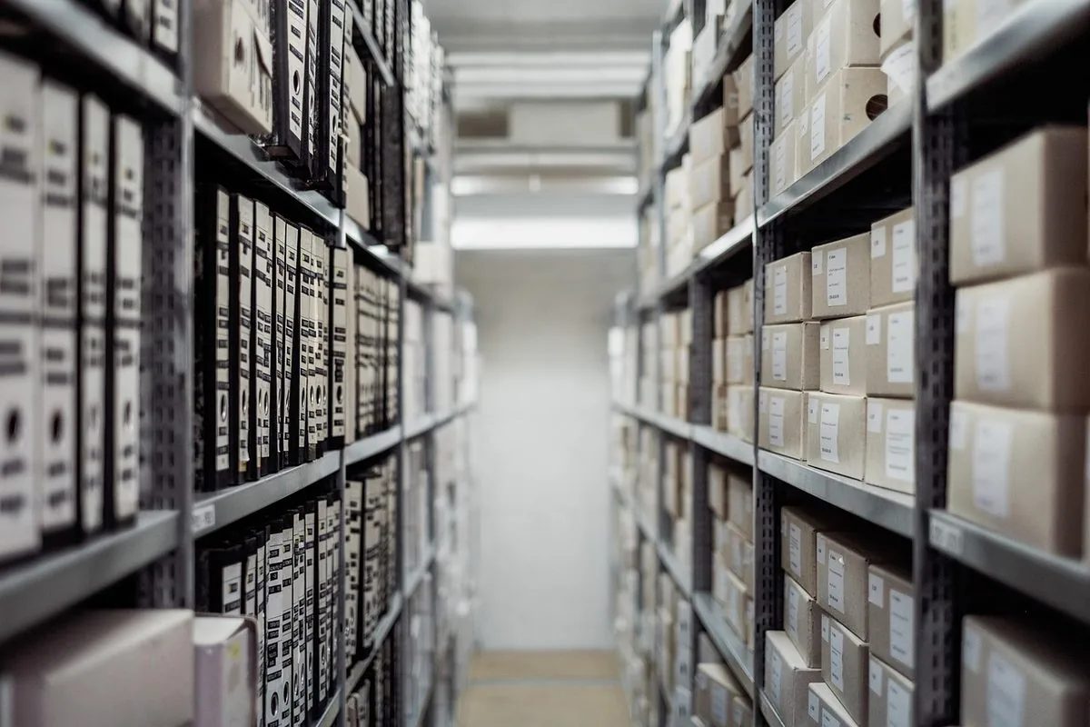 Regały archiwum z segregatorami i kartonami dokumentów