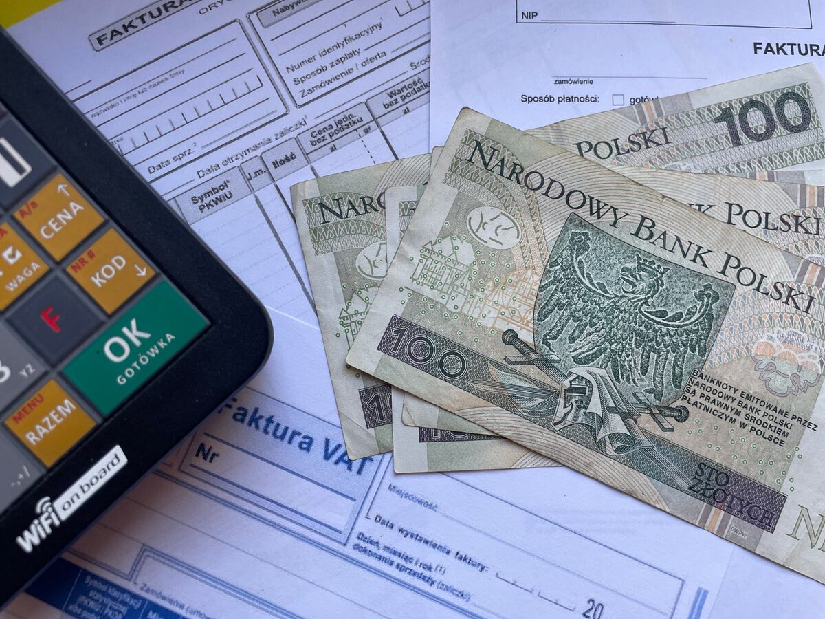 Faktury i banknot studuzłotowy obok kalkulatora