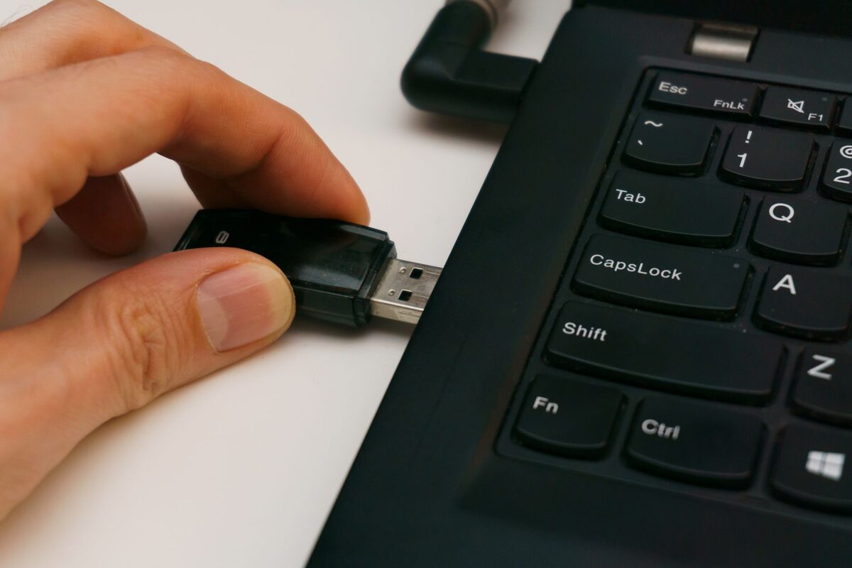 Dłoń z pamięcią USB przy klawiaturze laptopa