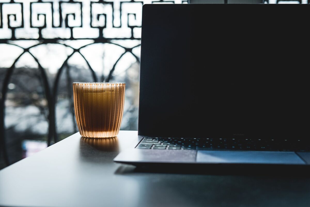 Laptop na stoliku z filiżanką kawy przy oknie