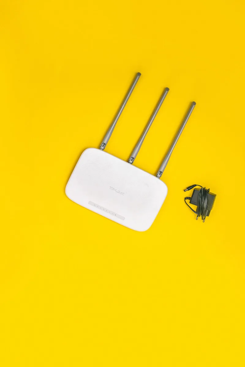 Router Wi-Fi z trzema antenami i zasilaczem na biurku