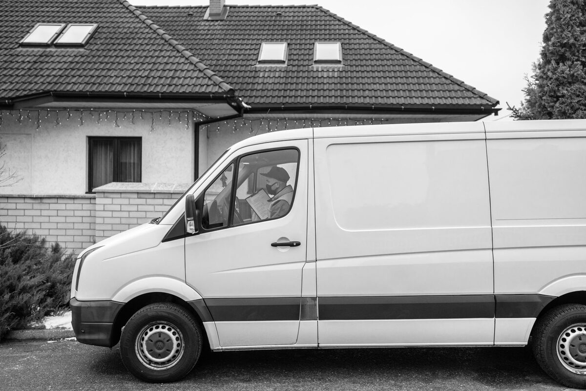 Biały samochód dostawczy zaparkowany przy domu