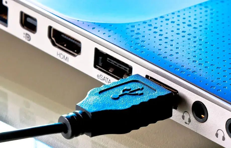 Zbliżenie na porty HDMI, eSATA i USB niebieskiego laptopa z podłączonym kablem USB