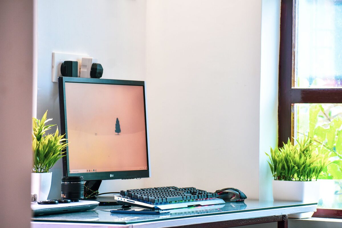 Monitor i klawiatura na biurku przy oknie