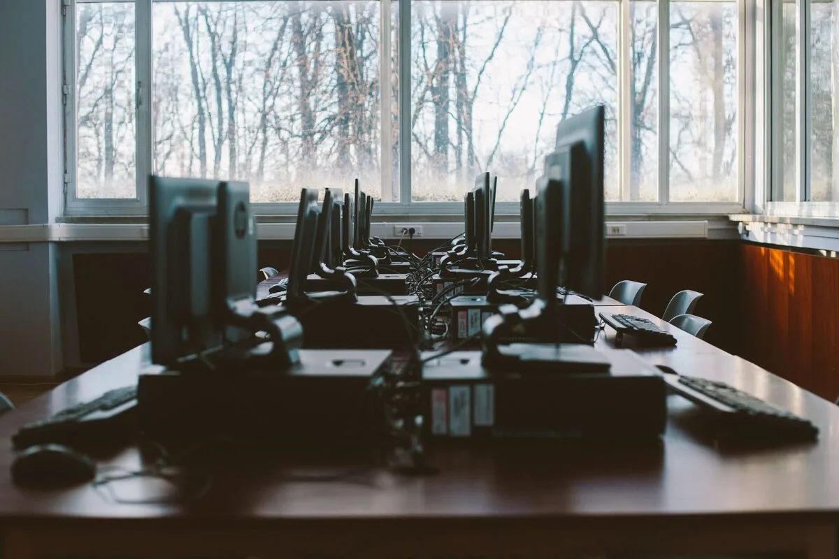 Sala komputerowa z rzędem monitorów przy oknie