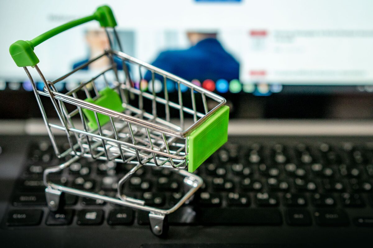 Miniaturowy wózek sklepowy postawiony na klawiaturze laptopa