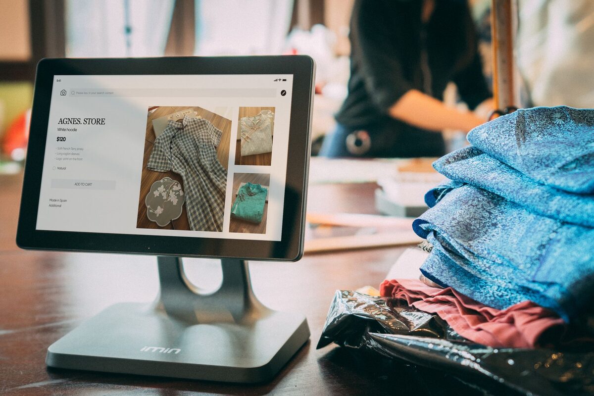 Tablet na podstawce w pracowni krawieckiej wśród tkanin