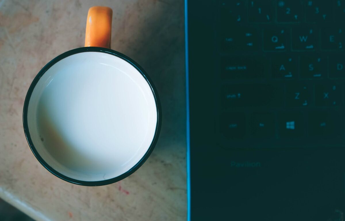 Kubek stojący tuż nad klawiaturą laptopa